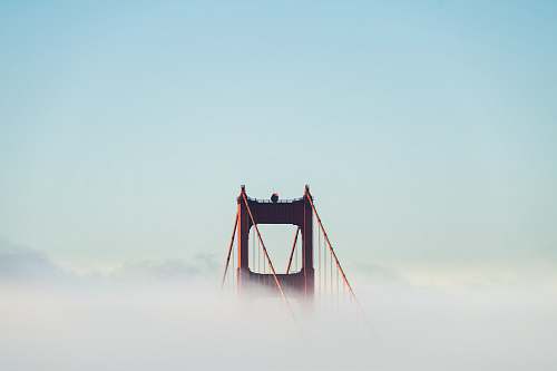 city red concrete bridge surrounded by clouds bridge