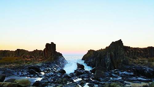 ocean landscape photography of body of water with rock formation cliff