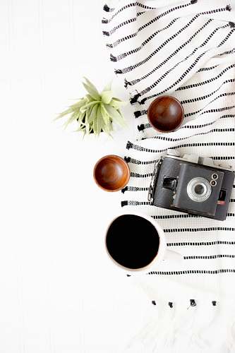 flatlay black and gray camera beside on brown wooden bowls linen