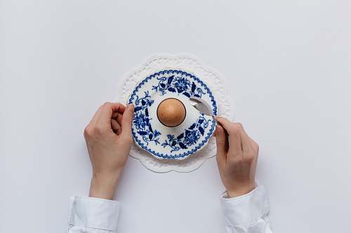 egg man holding white and blue caucer flatlay