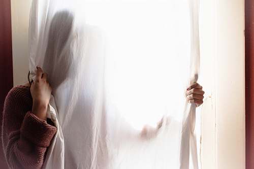 anonymous person hiding on white curtain hands