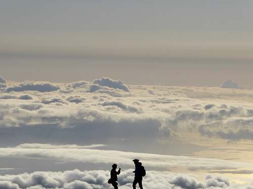 cloud silhouette of two people overlooking clouds during daytime sky