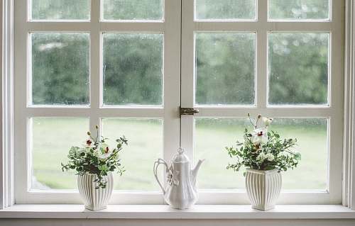 interior white teapot and tow flower vases on windowpane window