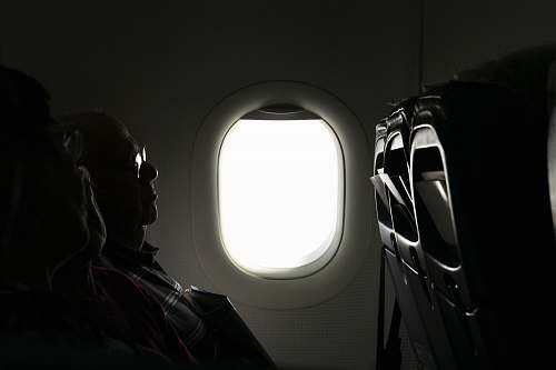 porthole two person sitting inside of airplane passenger