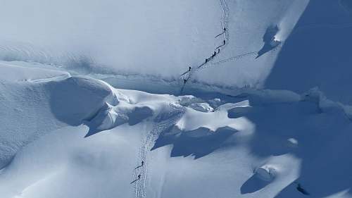 snow aerial photography of group of people trekking on snow mountain