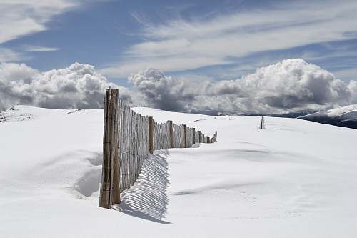 snow brown wooden fence on snow field under gray clouds snowy