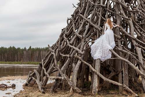 wood woman in white dress on piled wood logs river