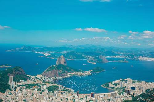 landscape aerial photography of buildings near blue sea and mountains scenery