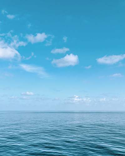 nature blue body of water under blue and white sky during daytime sky