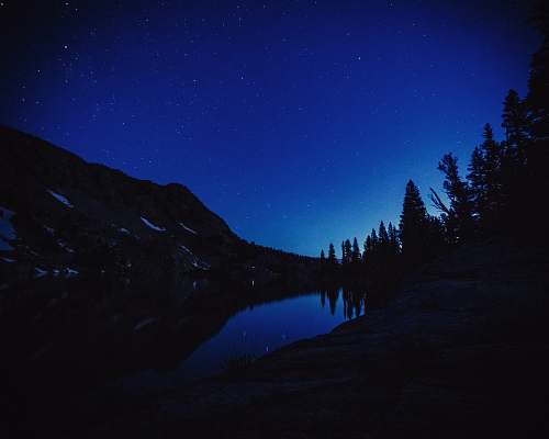 nature body of water beside mountain and trees outdoors