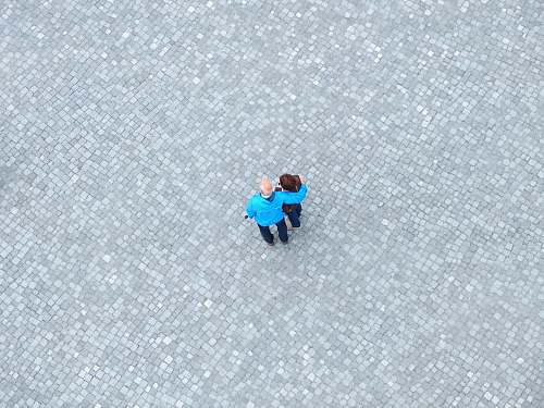 teal high-angle photo of man and woman standing in the middle of gray concrete paving grey