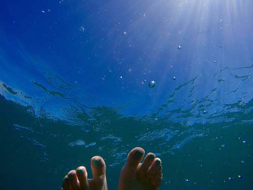 feet human feet on body of water during daytime underwater