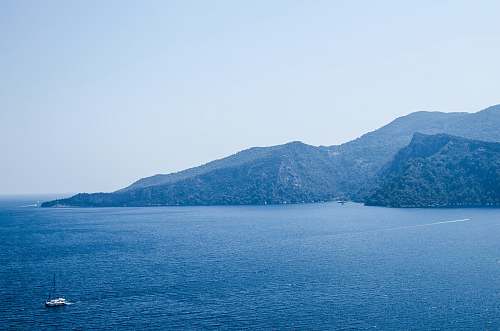 water landscape photography of sea and mountains under blue calm sky turkey