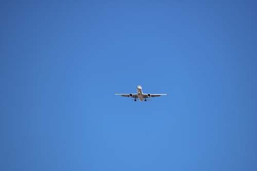 aircraft low angle photography of gray airplane under blue sky at daytime airplane