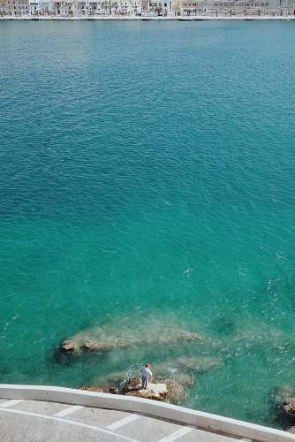 malta person standing on rock beside body of water sea