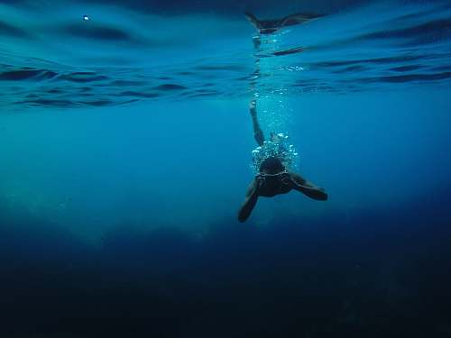 underwater person wearing goggles while swimming under body of water ocean