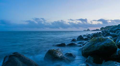 ocean rocks near calm sea under blue sky promontory