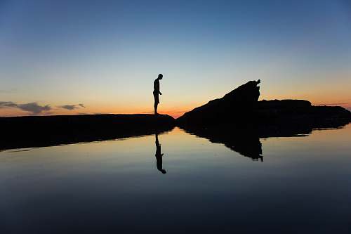 nature silhouette of man standing on land near body of water with reflection laguna beach