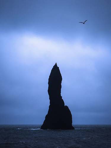 iceland silhouette of rock formation in the middle of sea cliff