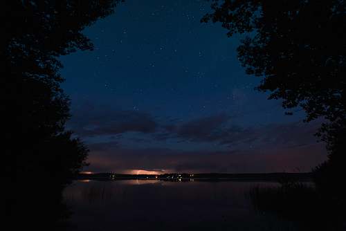 night silhouette of trees near body of water at nighttime thunder lake