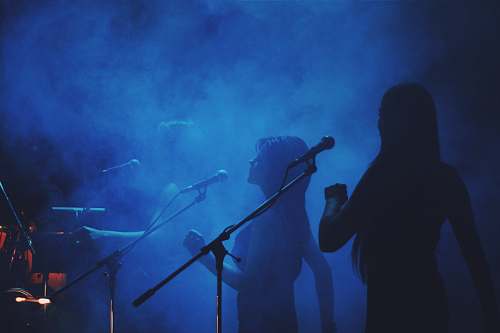 music silhouette photography of three women standing in front of microphone stands diver