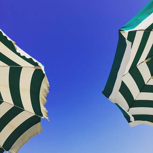 cushion worm's-eye view photography of two green and white patio umbrella under blue sky during daytime home decor