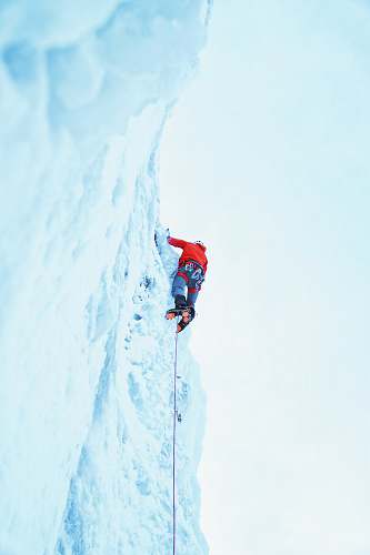brown person wearing red jacket climbing on glacier red