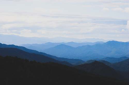 blue photo of mountains under blue sky mountain range