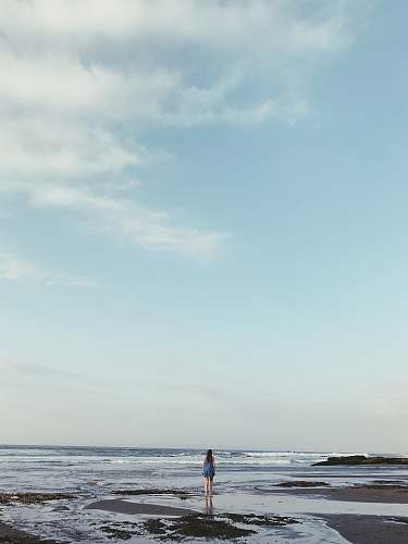 blue landscape photo of a woman on a beach outdoors