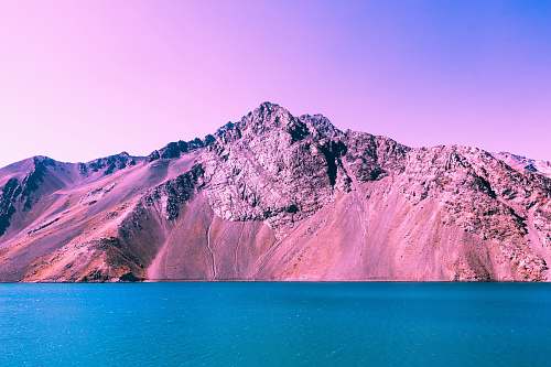 pink mountain beside body of water mountain
