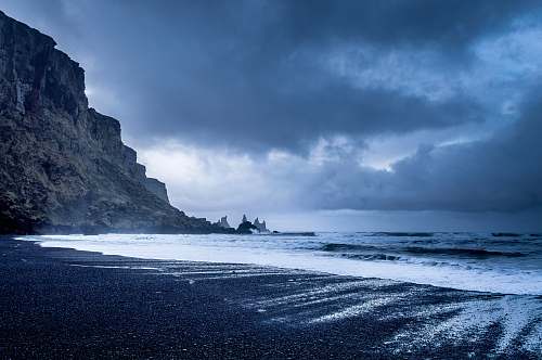 beach seashore near mountains during twilight coast