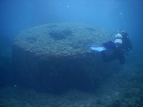 water man diving underwater near round structure person