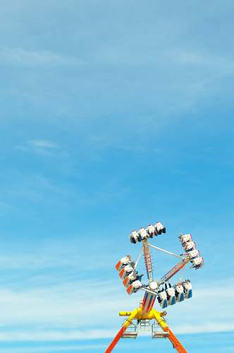 blue photo of yellow, orange, and blue amusement park ride under clear blue sky airplane