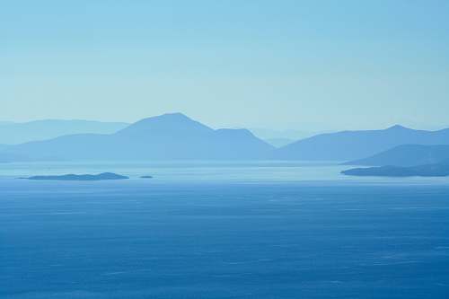 blue calm water beside mountains at daytime island
