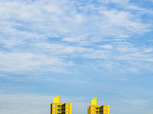 blue close up photography of two yellow buildings cloud