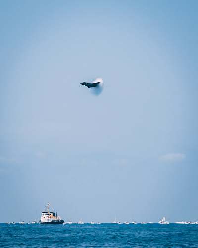 vehicle jet fighter creating sonic boom over the sea with ships boat
