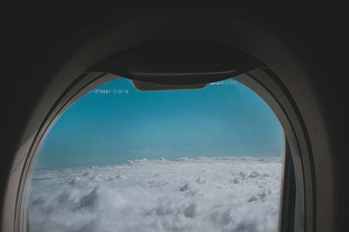 blue clouds through the plane window porthole