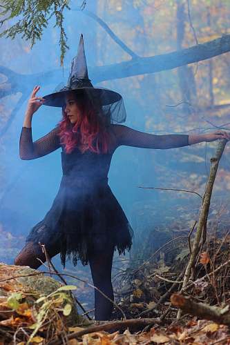 clothing woman in black witch costume standing beside rock person