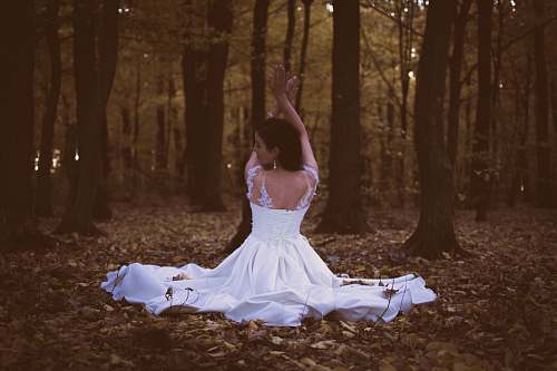 apparel woman in white sleeveless dress sitting on piles of leaves female