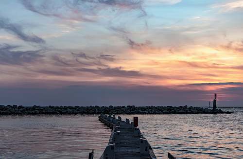 pier brown wooden dock under gray and orange skies sea