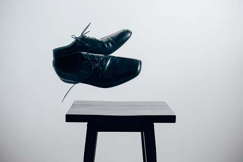 chair pair of black leather dress shoes over brown wooden table shoes