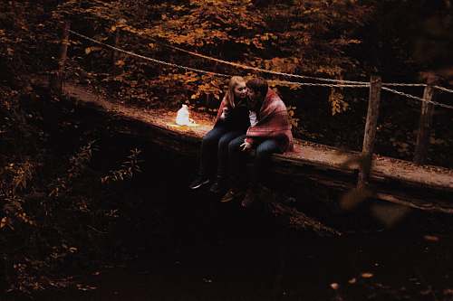 person couple sitting on bridge people