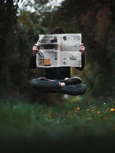 newspaper person holding a news paper during daytime text