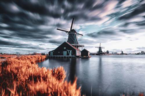 engine windmill house beside body of water during day motor