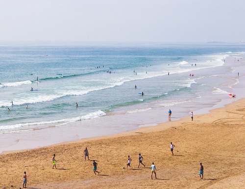 coast group of people on shore during daytime beach