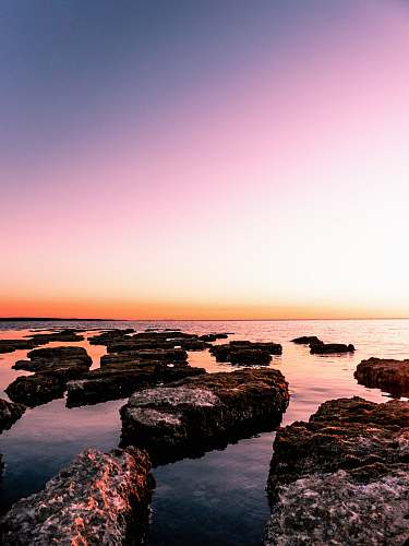 outdoors rocky island beside beach sunset