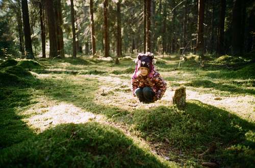 human girl sitting in the middle of green woods people