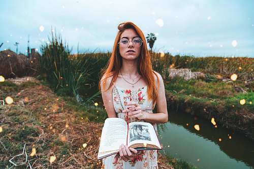 human woman holding an open book near the creek people