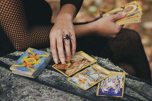 human woman holding tarot cards finger