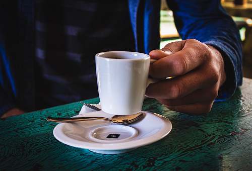saucer person holding white ceramic mug on saucer cup